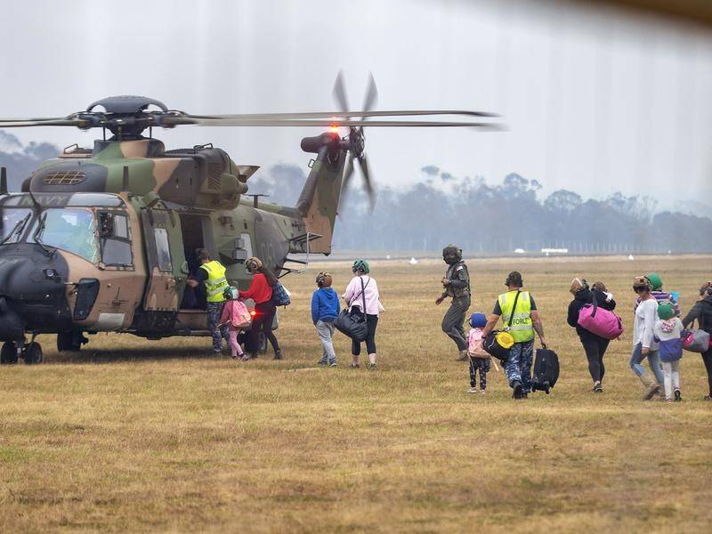People board a helicopter as the fire-ravaged community of Mallacoota is evacuated in January.
