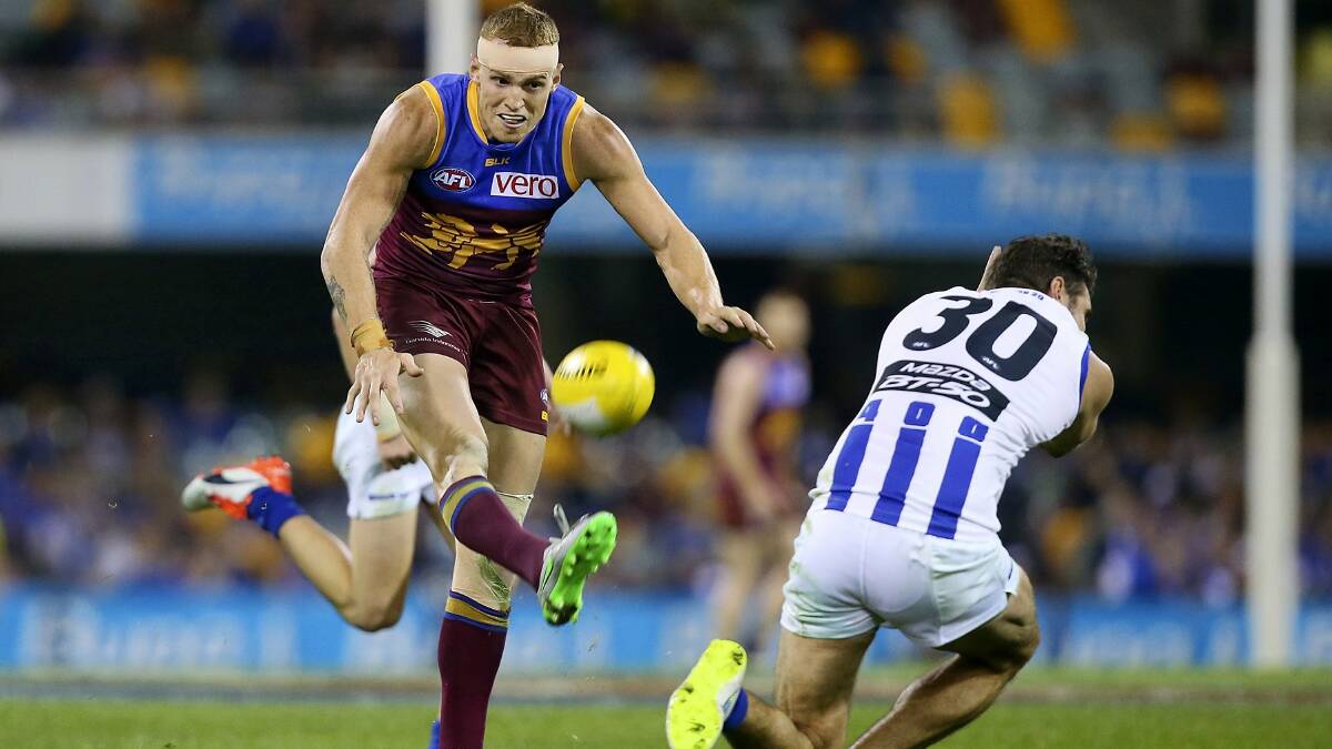 Brisbane’s  Mitch Robinson  gets his kick away as North Melbourne’s Jarrad Waite takes evasive action in Saturday night’s clash at the Gabba. Picture: GETTY IMAGES