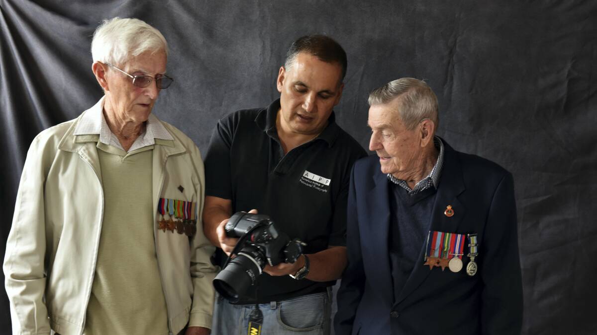 Photographer Philip Kuruvita shows his pictures to returned soldiers Ken Manson and John Milbourne.

 Picture:  SCOTT GELSTON