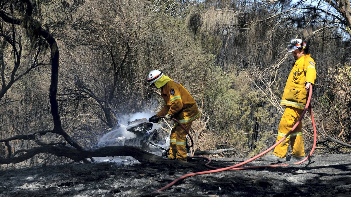 Fire crews at work around homes in Cunningham Street at St Helens following Sunday’s bushfire.  Pictures: MARK JESSER