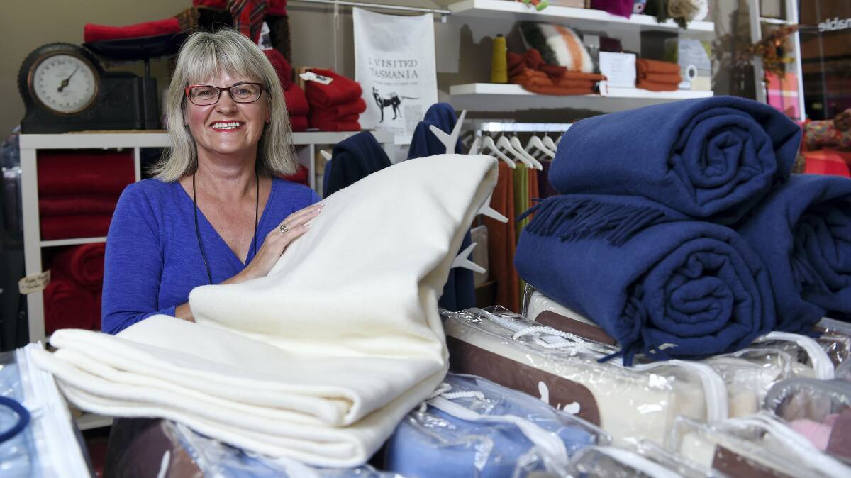 Store owner Penny Rundle with  a merino cot blanket from Waverley Woollen Mills. Picture: MARK JESSER