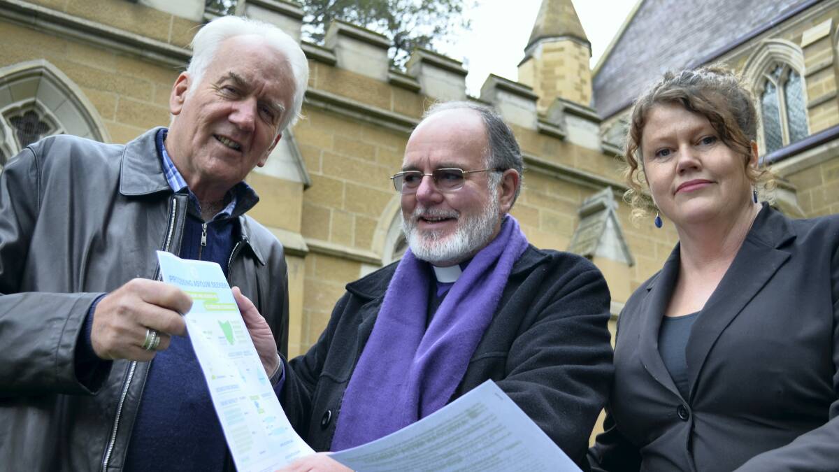 Damon Thomas, Bishop John Harrower and Multicultural Council chief executive Anna Reynolds look over the ``Tasmania solution''. 