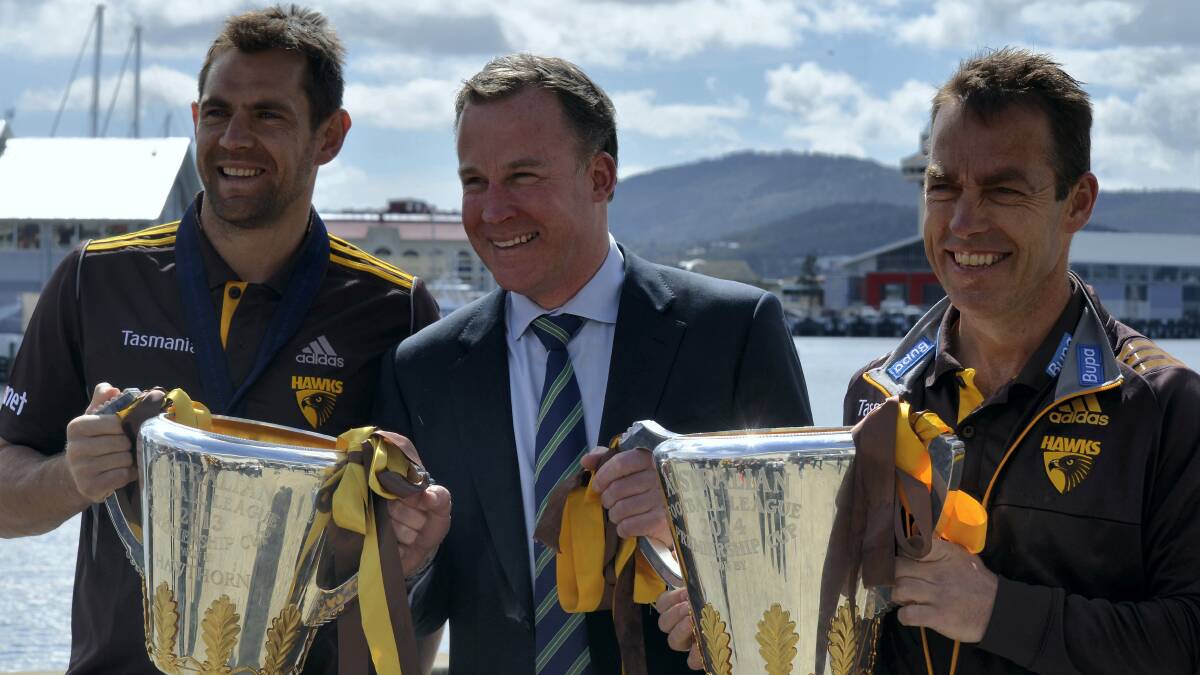 Hawthorn captain and Norm Smith medallist Luke Hodge, Premier Will Hodgman  and Hawthorn coach Alastair Clarkson with the team’s two AFL premiership cups in Hobart.