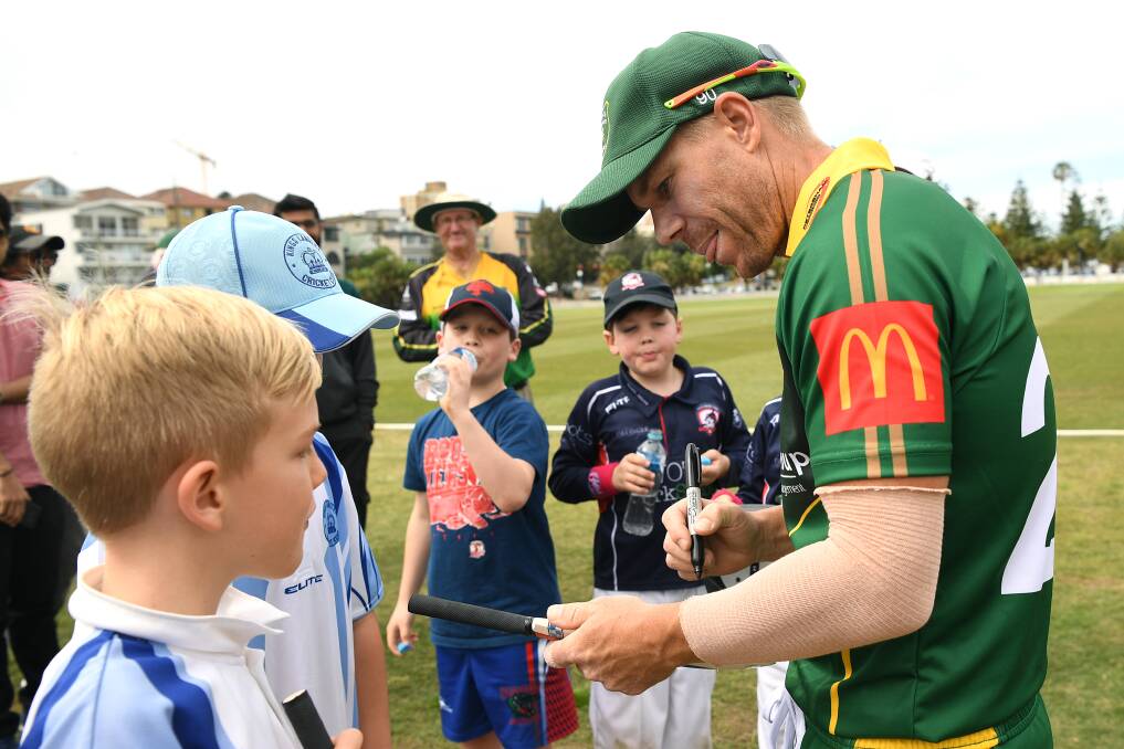 David Warner signs autographs during a match for Randwick Petersham against St George at Coogee Oval in Sydney, on Saturday. Picture: AAP 