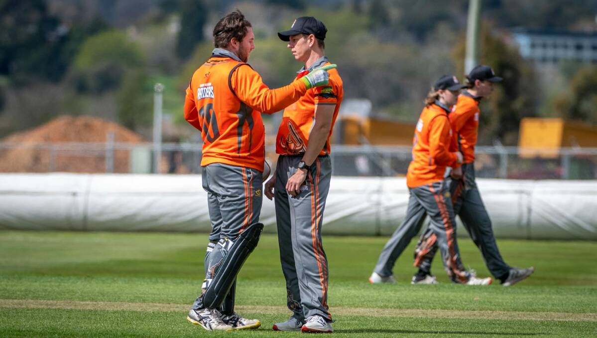 Uni studies: Raiders wicket keeper Alistair Taylor talks tactics with bowler Evan Gulbis against University at Windsor Park in October. Picture: Paul Scambler
