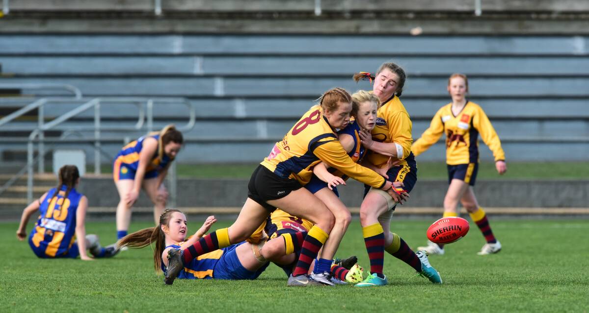 CRUNCH: Mia King and Bianca White, of East Launceston Junior Football Club, tackle Anabel Thomson of Evandale Football Club.