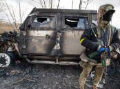 A Ukrainian soldier stands beside a burnt-out Russian Tigr fighting vehicle destroyed by his unit east of the strategic port city of Mykolaiv earlier this month. Picture: Getty Images