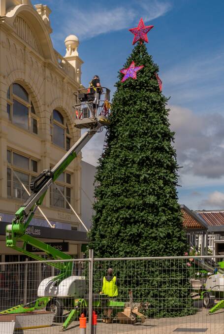 JOLLY: Workers hanging the stars on the Christmas tree in the Brisbane Street Mall. The tree takes four days to set up. Picture: Phillip Biggs