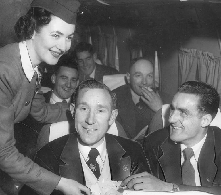 Inside a Skymaster Kattana airplane in 1953 with the air hostess Judy Thorpe offering a barley sugar to local football players Len McCankie and Arthur Hodgson.
