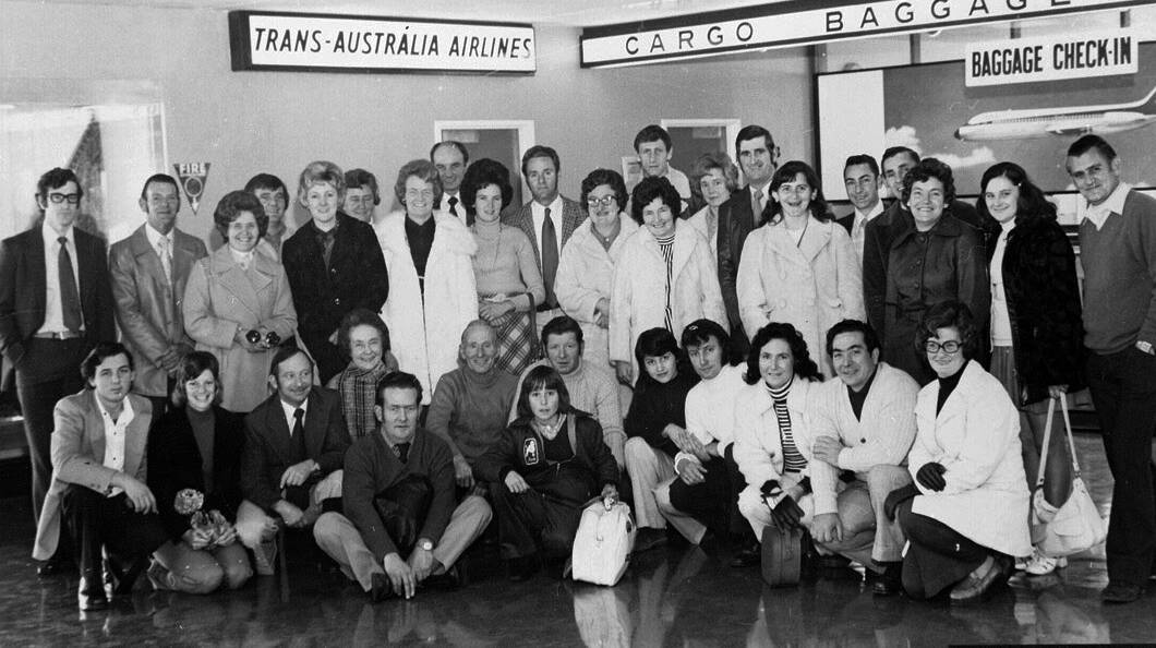 Group portrait of Peters Ice Cream Pty. Ltd. staff at the Launceston Airport, next to the baggage check-in of Trans-Australia Airlines (T.A.A.)