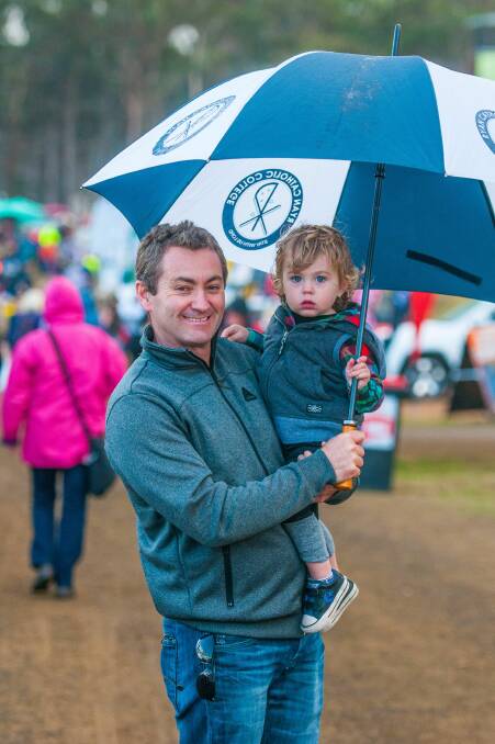 KEEPING DRY: Devonport's Gary and Willem Jordan, 2, stay out of the rain at Quercus Park on the final day of Agfest 2017. Picture: Scott Gelston