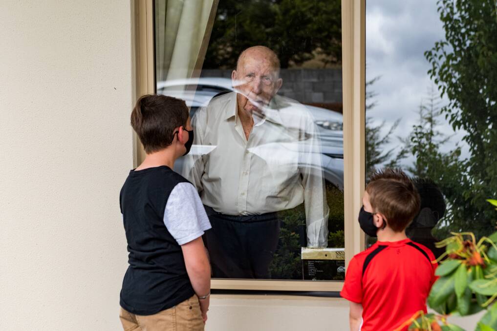 PANE: Deegan and Nate Medcraft seeing their 97-year-old great-great-grandfather Cyril Jago in his locked down aged care facility. Picture: Phillip Biggs
