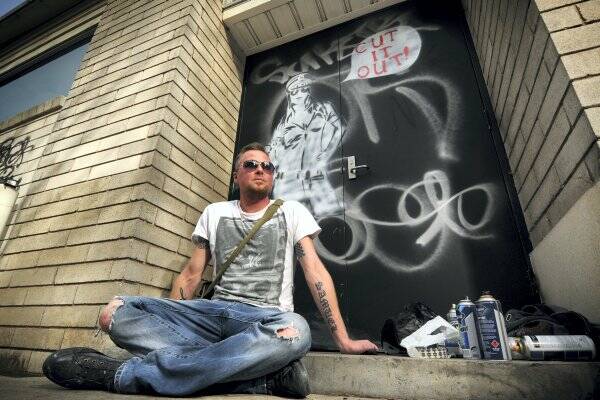 Stencil art course leader and artist Ben Miller paints over graffiti.  Picture: PHILLIP BIGGS