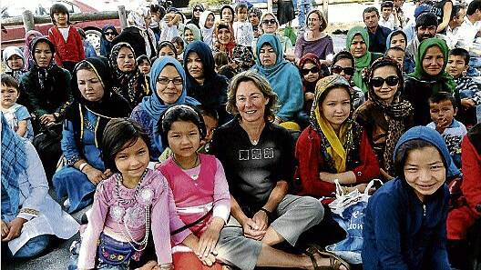 Sharon Wright from the Migrant Resource Centre sits among Afghan families at the community picnic yesterday.  Picture: NEIL RICHARDSON