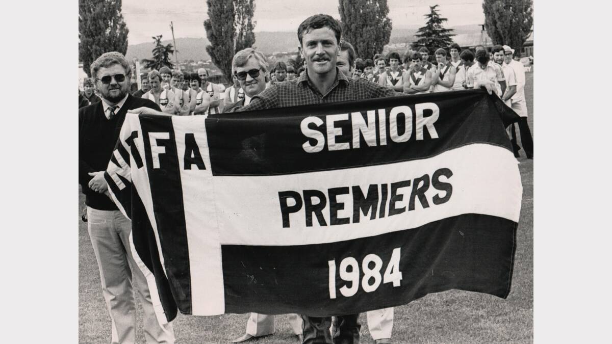 A happy Scottsdale captain-coach Greg Lethborg shows off his reigning premiers flag at the Lighting Premiership of 1985.