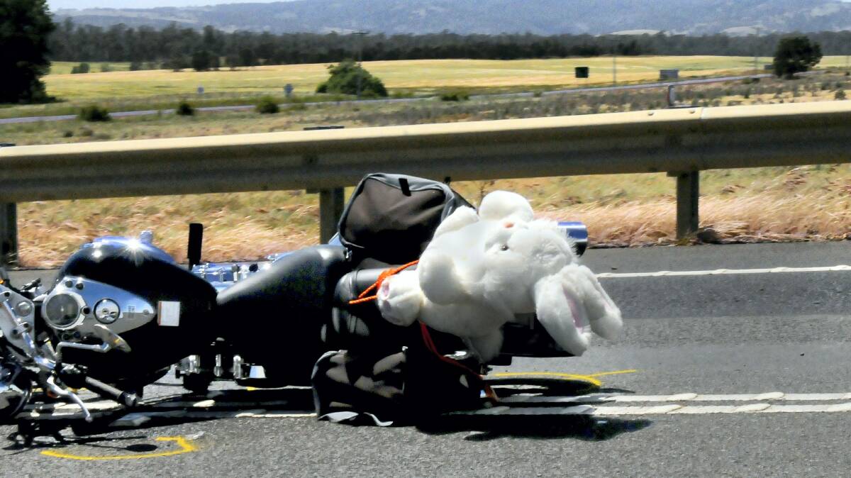 The victim's motorcycle lies on the highway with her soft toy donation still strapped on.