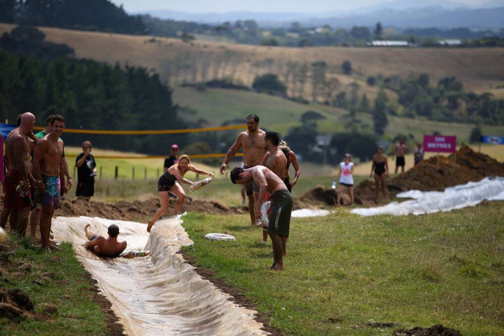People enjoy the muddy thrills and spills on a waterslide dug into a hillside in Waimauku, New Zealand. Photo: Getty Images