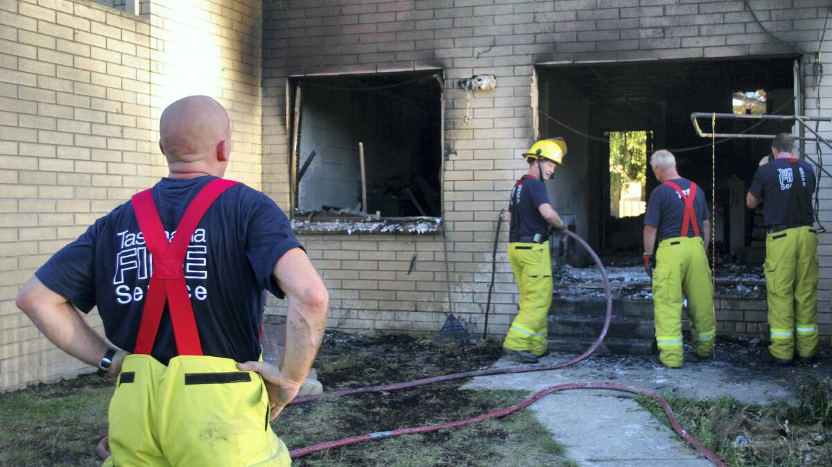 Firefighters inspect the damage at Housing Tasmania property in Pioneer Parade, Ravenswood, last night.