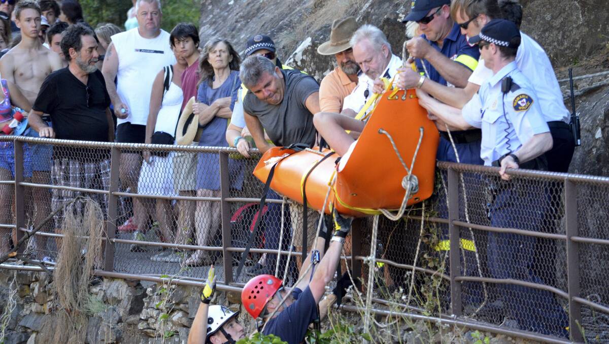 Police search and rescue officers help a teenage boy at Cataract Gorge, after he suffered a suspected lower leg fracture yesterday.