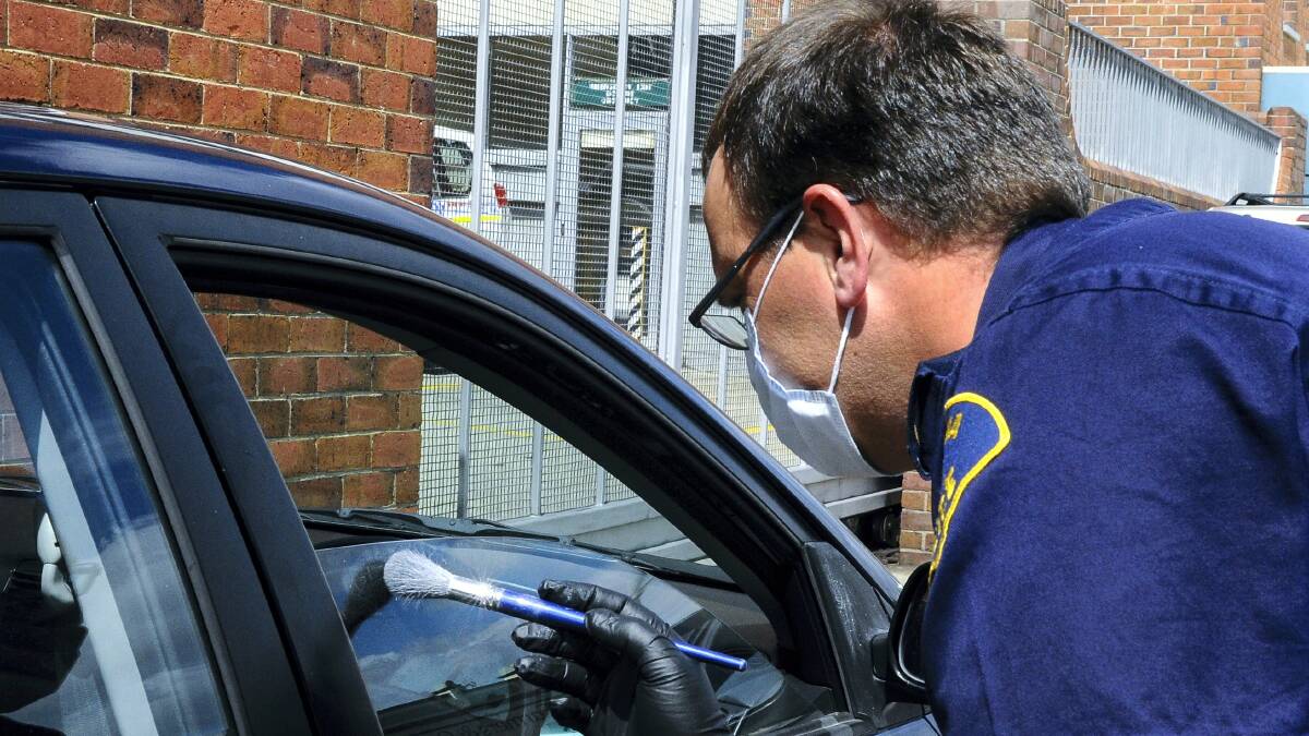 Senior Constable Rodney Walker examines a car for evidence of theft.  Picture: NEIL RICHARDSON
