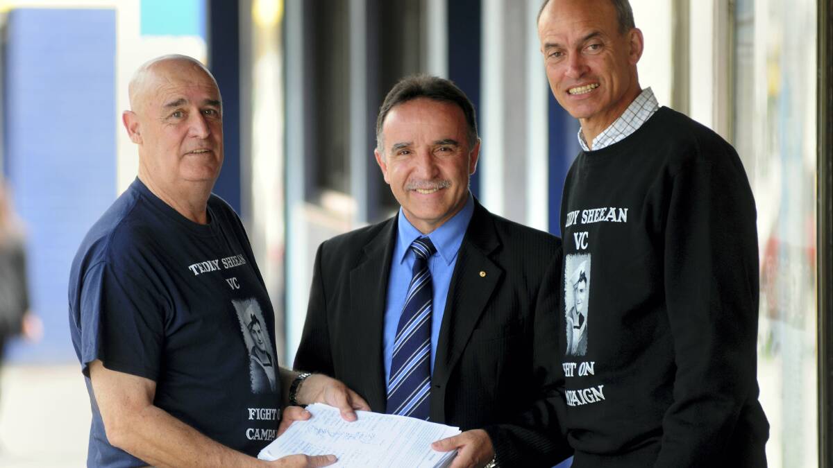 Teddy Sheean's nephew Garry Ivory, of Launceston, presents a 5175-signature petition to Bass Liberal MHR Andrew Nikolic as Guy Barnett, of Launceston, looks on.  Picture: PETER SANDERS