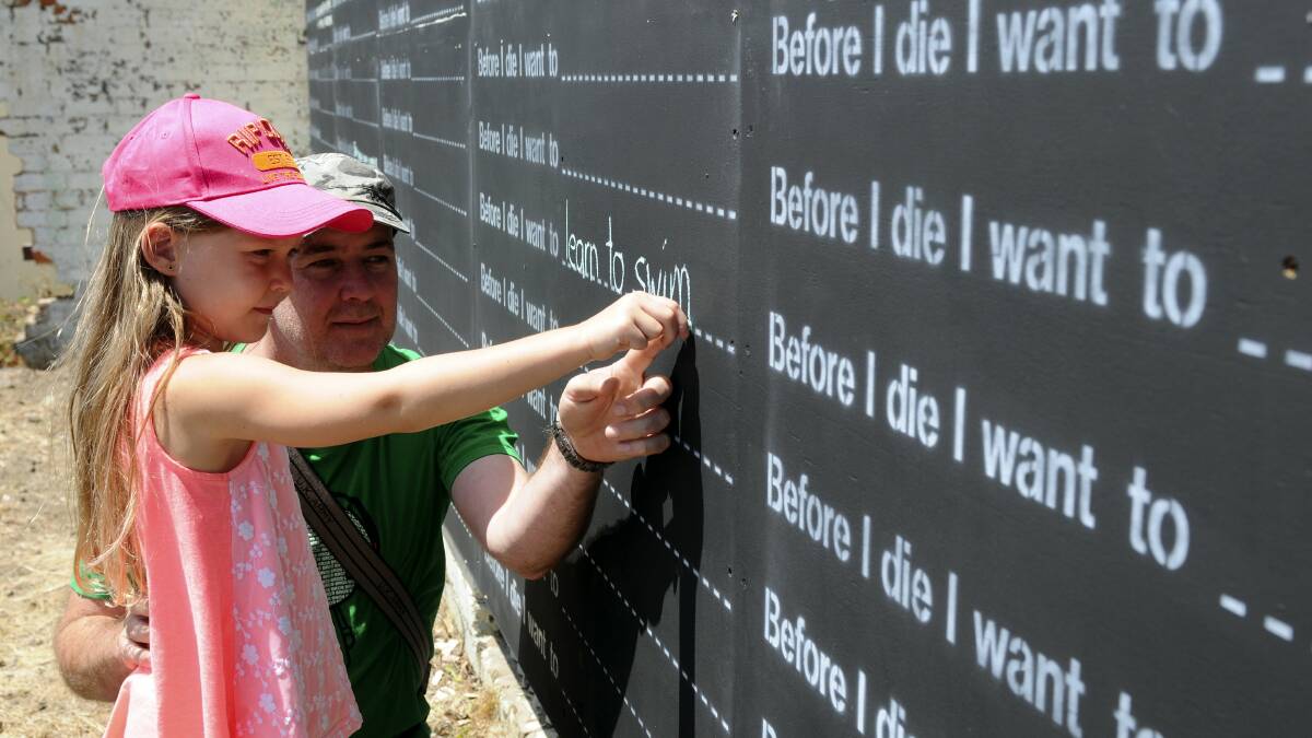 April Esdale and father Brad Esdale, of Brisbane, writing on the Before I Die wall in Launceston's Boland Street. Picture: PAUL SCAMBLER
